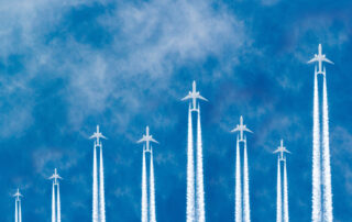 Airplanes flying in parallel in the blue sky forming a stock market curve graph.